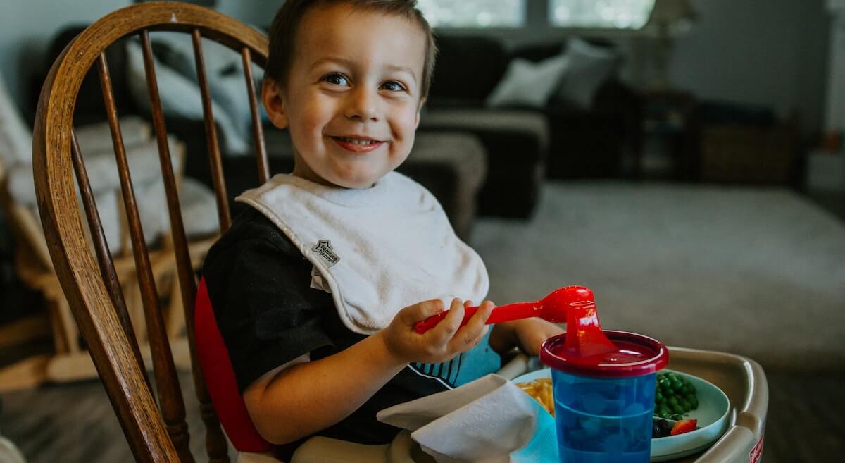 young boy sitting and eating on high chair